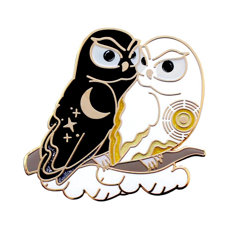 Enamel pin of a black owl representing night cuddling with a white owl representing day