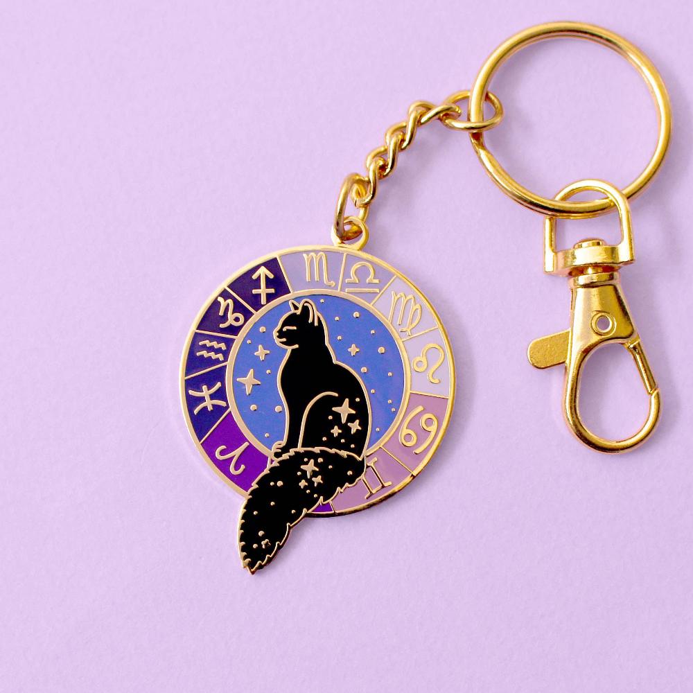 Gold keychain featuring black cat in a starry window surrounded by the zodiac wheel