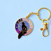 Gold keychain featuring black cat in a starry window surrounded by the zodiac wheel